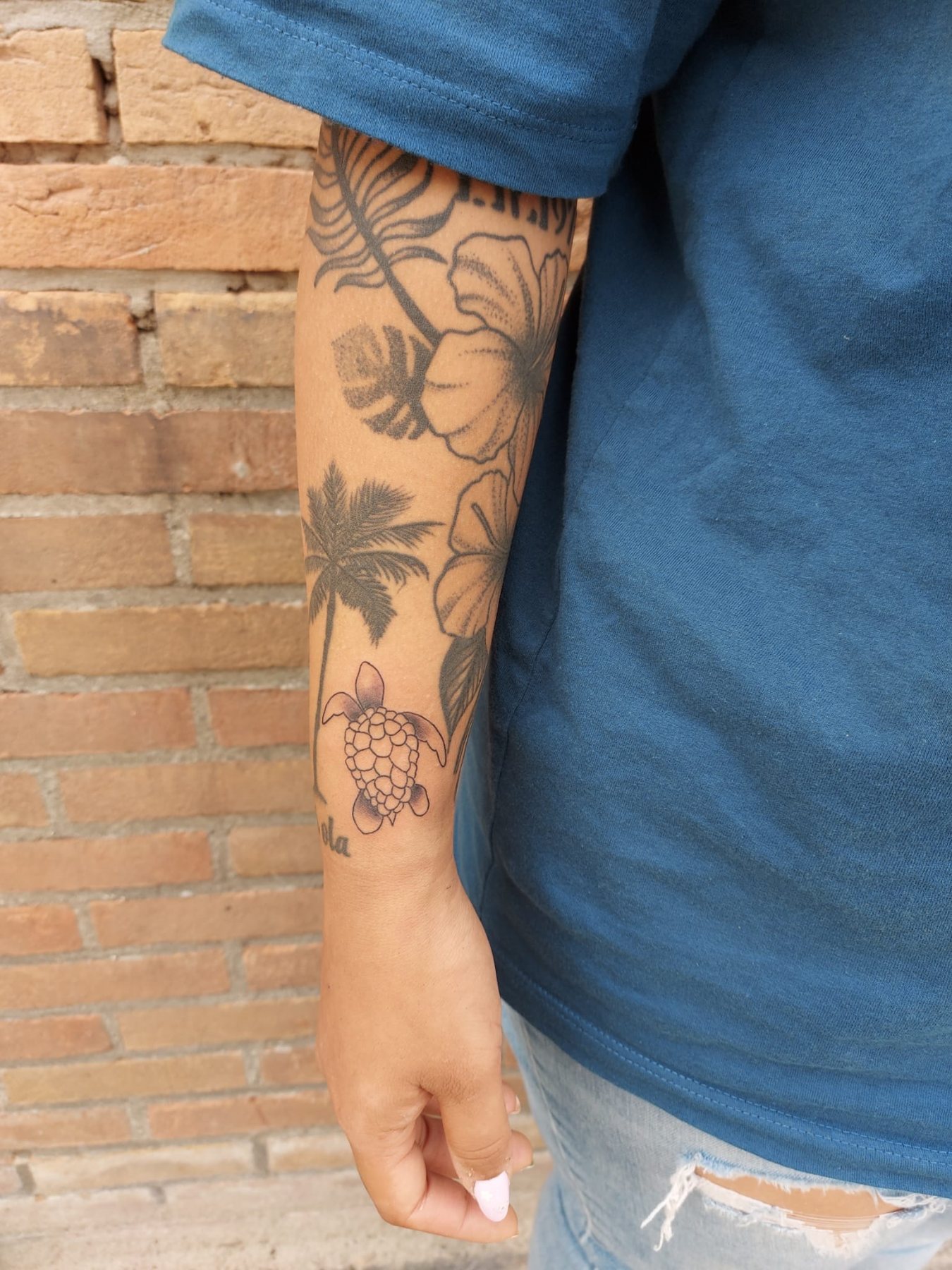 Onderarm vol bloemen, palmbladeren en een schildpad