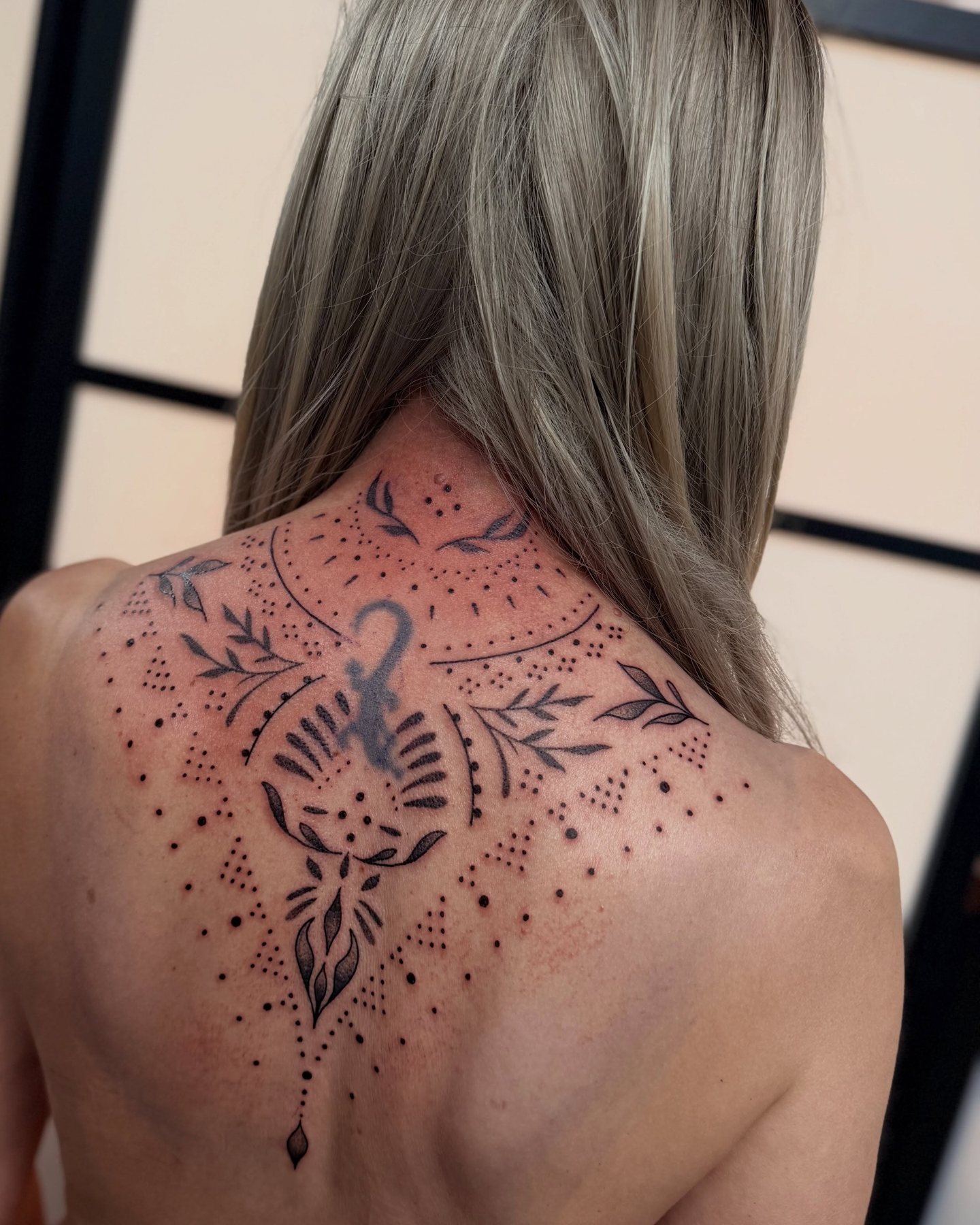 Ornamentaal backpiece met stippen en bladeren tussen de schouderbladen