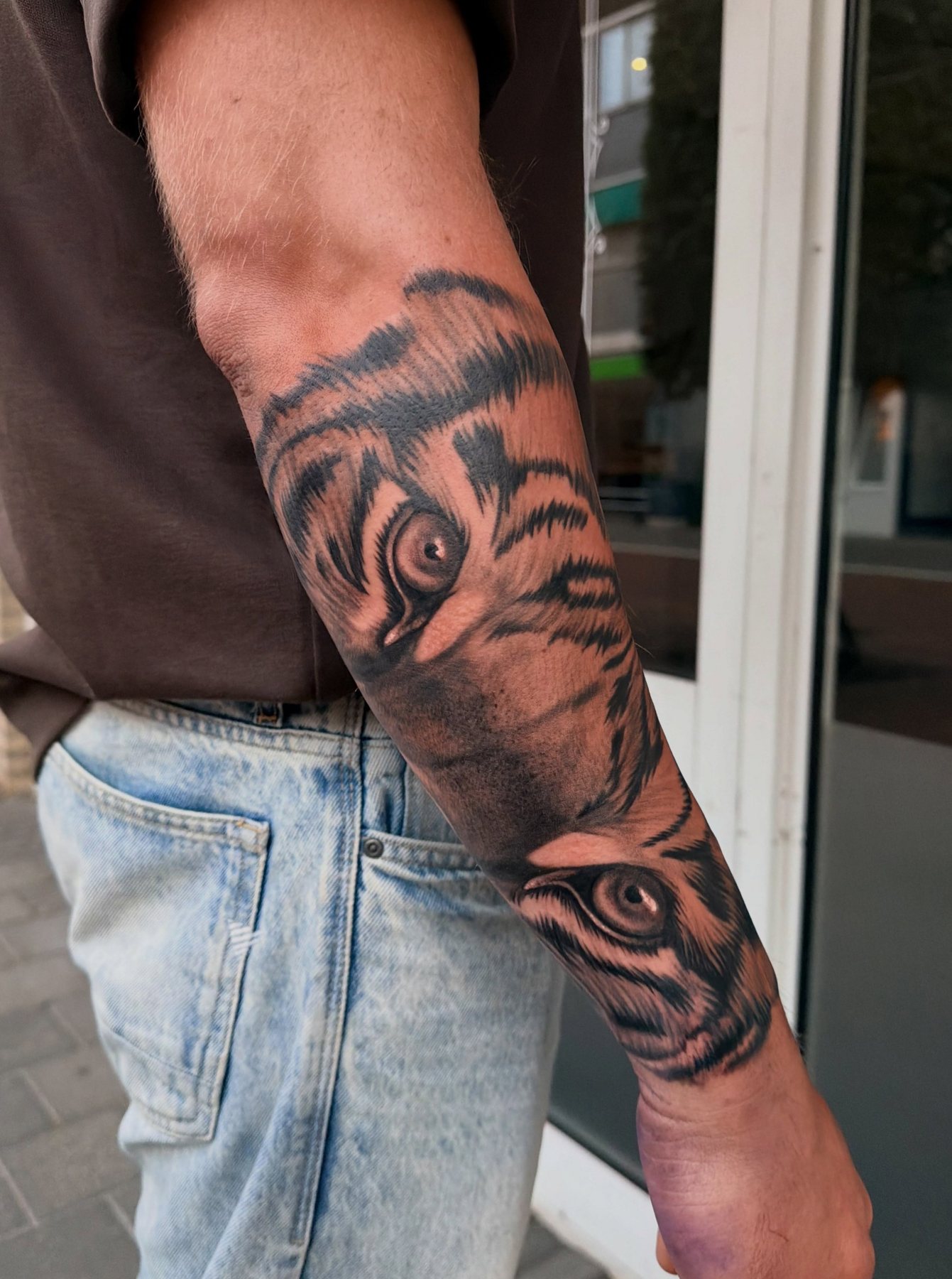 Tijgerogen in black & grey op een onderarm, voor het raam van de studio